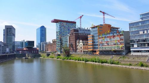 Buildings by river against sky in city