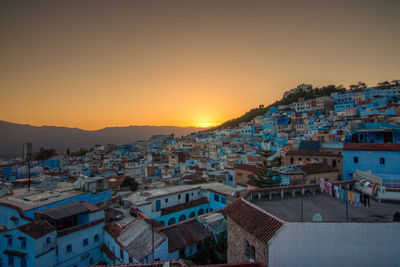 High angle view of illuminated cityscape against sky at sunset