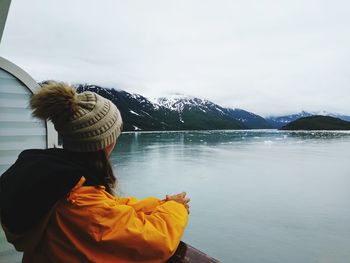 Rear view of woman in lake against sky during winter