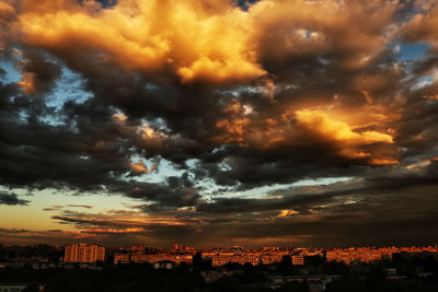 Cityscape against cloudy sky at sunset