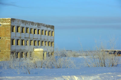 Built structure on snow covered field against sky