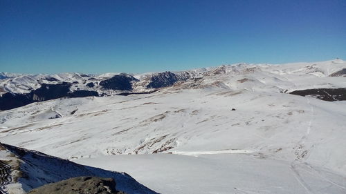 Scenic view of snowcapped mountains against clear blue sky