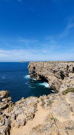 Rock formations on shore against blue sky