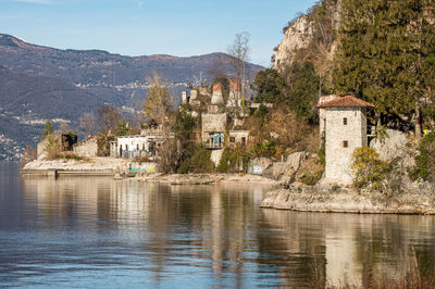 Old ruined furnaces with chimneys with red bricks reflecting on the water of lake maggiore 