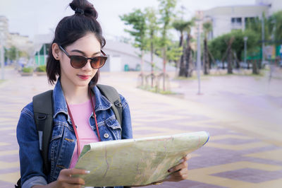 Young woman reading map on street in city