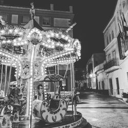 Illuminated carousel in city at night