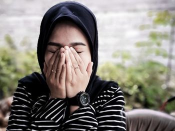 Close-up of young woman wearing hijab covering mouth