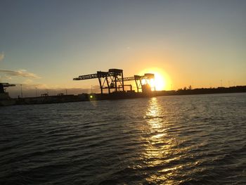 Silhouette commercial dock against clear sky during sunset