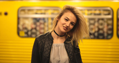 Portrait of beautiful woman standing against yellow train