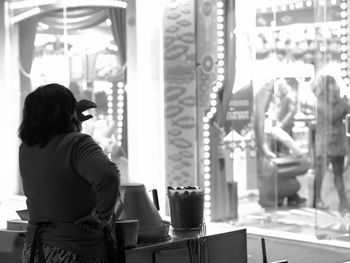 Rear view of woman looking through window