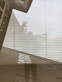 Man reflecting on glass window while standing by building