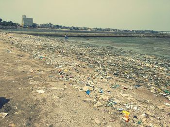 Garbage on beach against sky in city