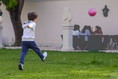 Rear view of boy playing with ball on field