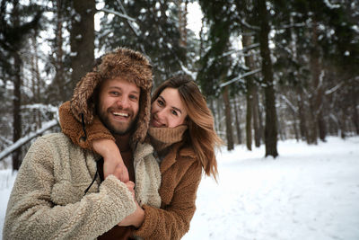 Portrait of smiling couple embracing against trees in forest