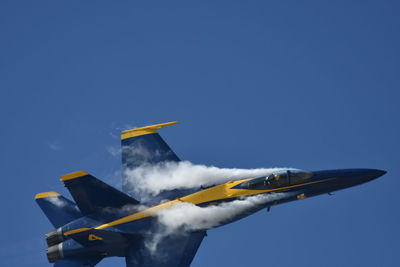 Low angle view of airplane flying against clear blue sky