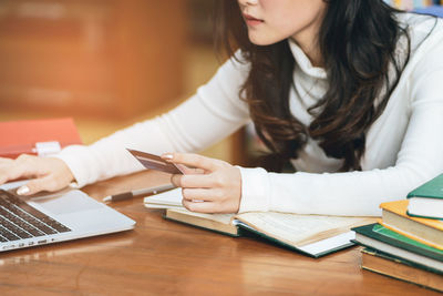 Midsection of woman using mobile phone while sitting on table