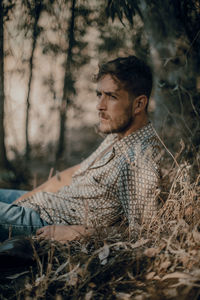 Side view of young man sitting on field