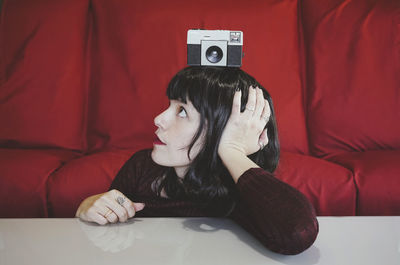 Woman with camera on head in front of red couch