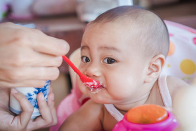 Cropped hand of mother feeding food to baby daughter