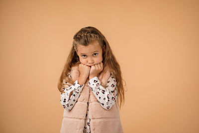 Young woman standing against yellow background