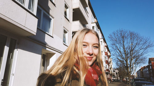 Portrait of teenage girl standing against building