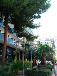 Trees and buildings in city against clear sky