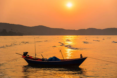 Sailboat on sea against orange sky