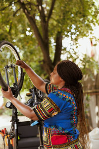 Rear view of woman with bicycle against trees