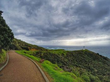 Scenic view of road by sea against sky