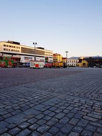 Street by footpath against sky in city