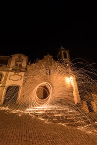 Light trails on illuminated city against sky at night