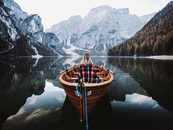 Rear view of woman in boat on lake against mountains