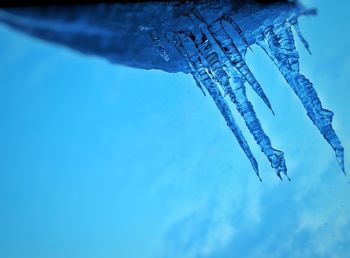 Low angle view of frozen water against blue sky