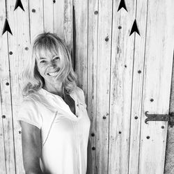 Portrait of smiling woman standing against wall