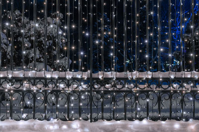 Ornamental, metal fence decorated with led illumination. snow covering metalwork. 