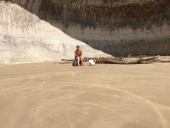 Full length of man sitting on rock