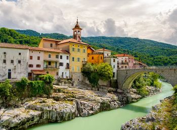 Arch bridge over river amidst buildings against sky