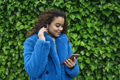 Young woman looking at camera while standing on green mobile phone