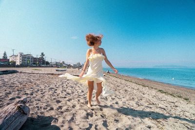Rear view of woman standing at beach