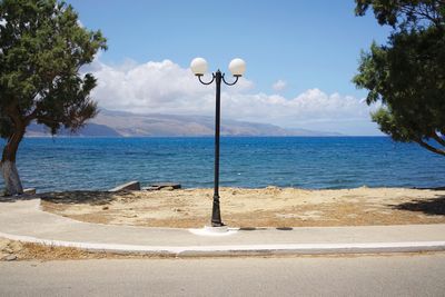 Street light by sea against sky