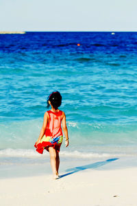 Rear view of woman on beach against sky