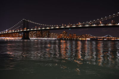 Illuminated bridge over river against sky at night