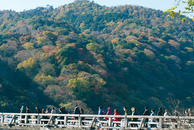 People walking on bridge against mountain