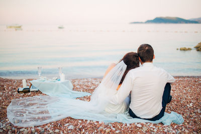 Rear view of couple sitting on beach