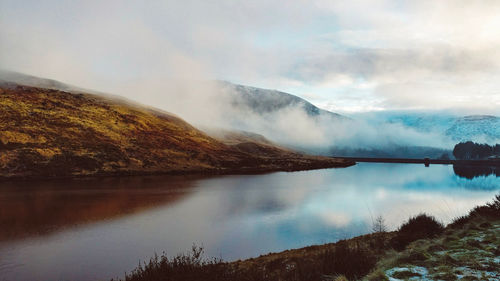 Scenic view of lake by mountains against sky