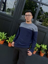 Portrait of young man standing on potted plant