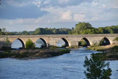 Arch bridge over river against sky