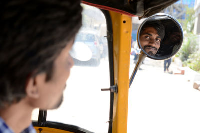 Portrait of jinrikisha driver seen from rear-view mirror