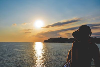 Rear view of silhouette man against sea during sunset