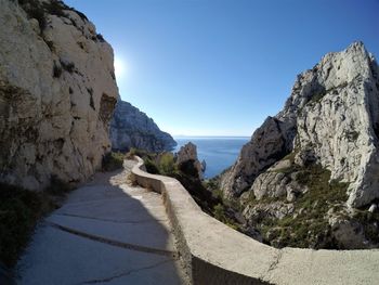 Rock formations by sea against clear blue sky